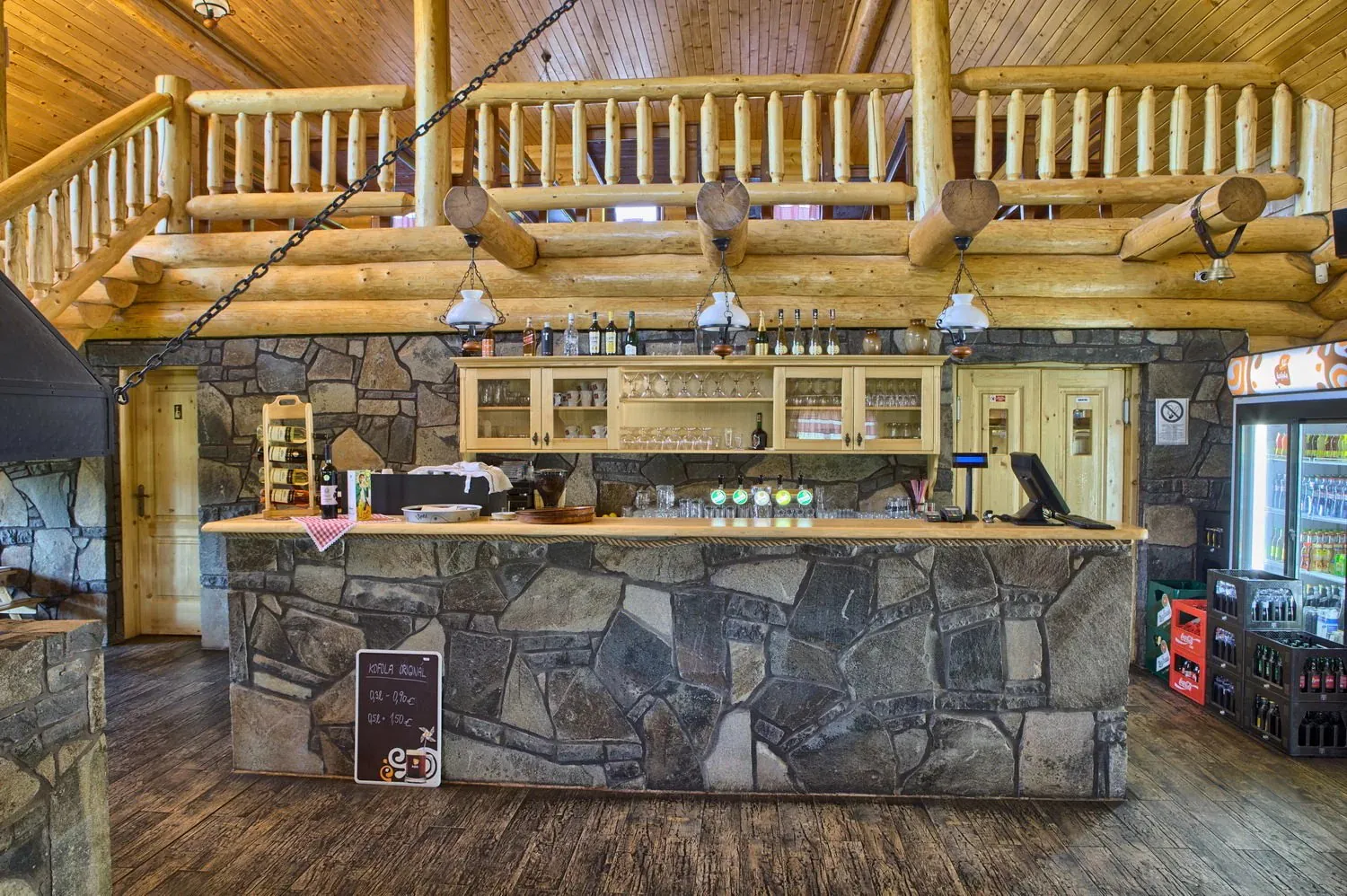 Kamenný bar a výčap koliby pod dreveným zrubovým stropom